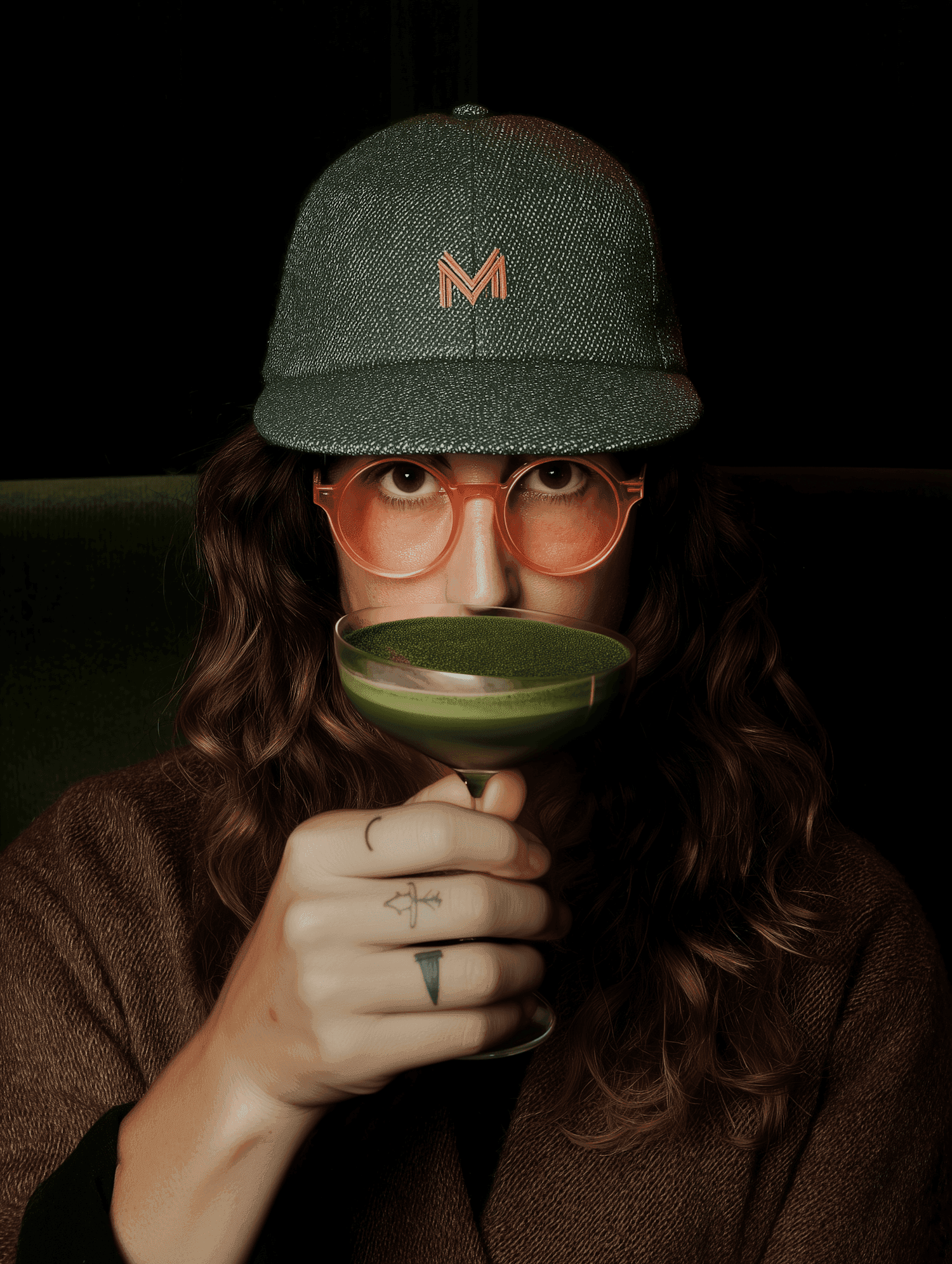 Woman in a green cap sipping a green cocktail